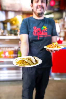 A person holding a plate of tacos