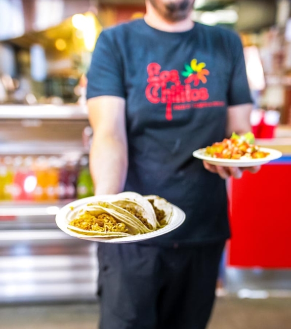 A person holding a plate of tacos