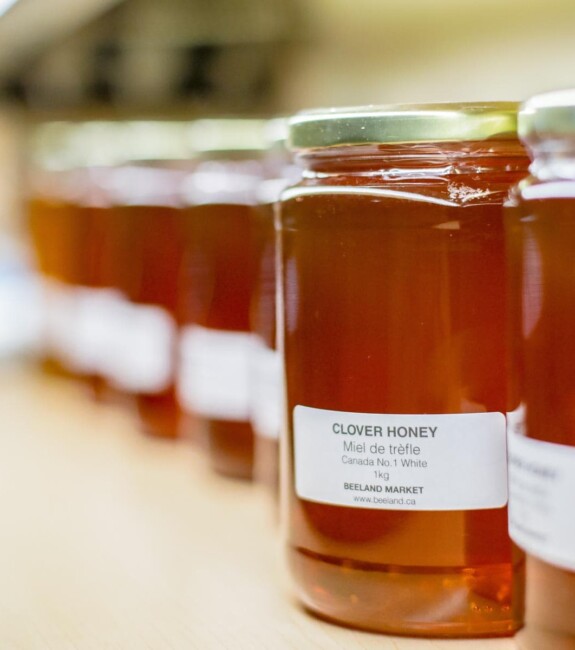 Glass bottles of honey lined up on a shelf